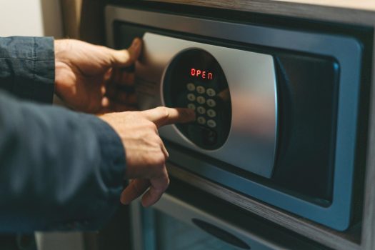 Adult man in blue jacket uses safe in the hotel room